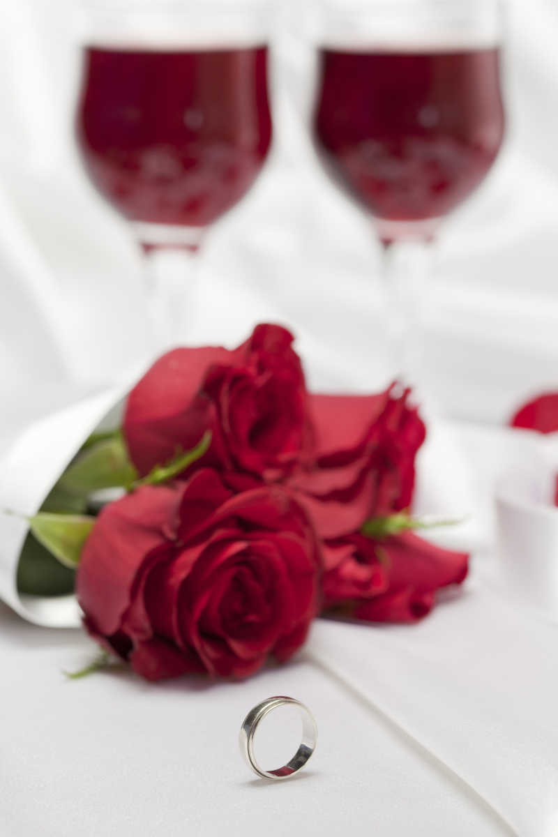 白布上的红玫瑰戒指和红酒
