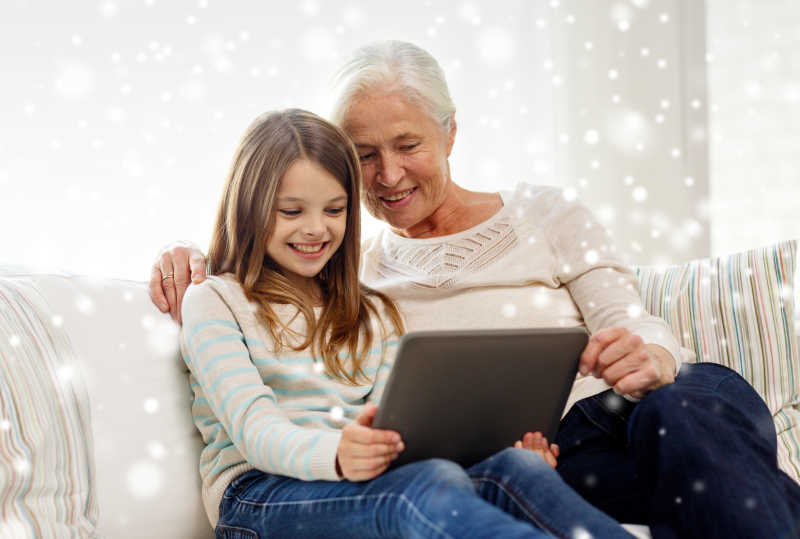 在家里玩平板电脑的奶奶和小女孩