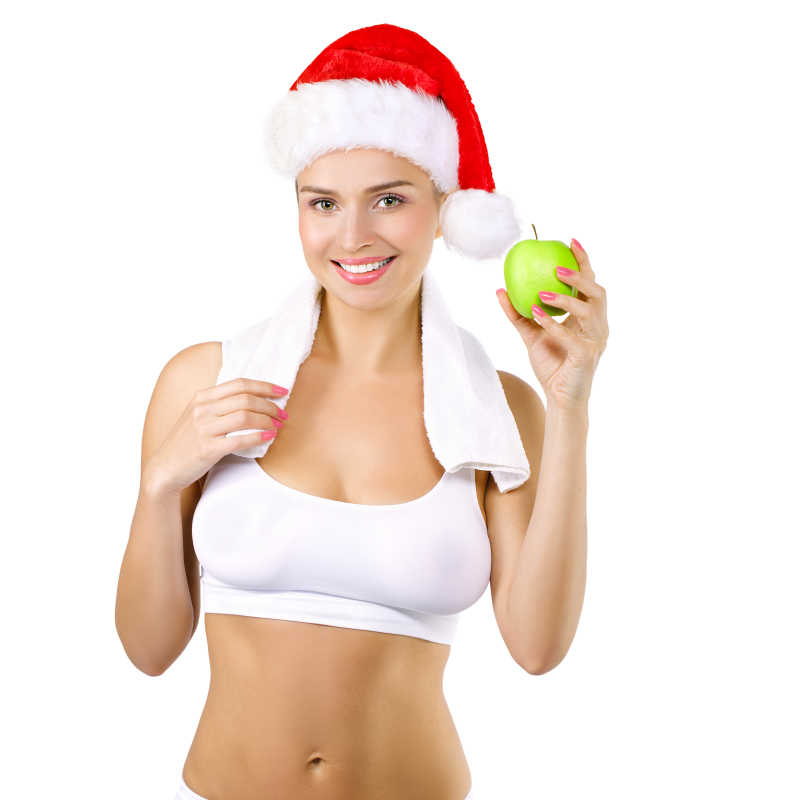 戴圣诞帽的健身美女拿着苹果