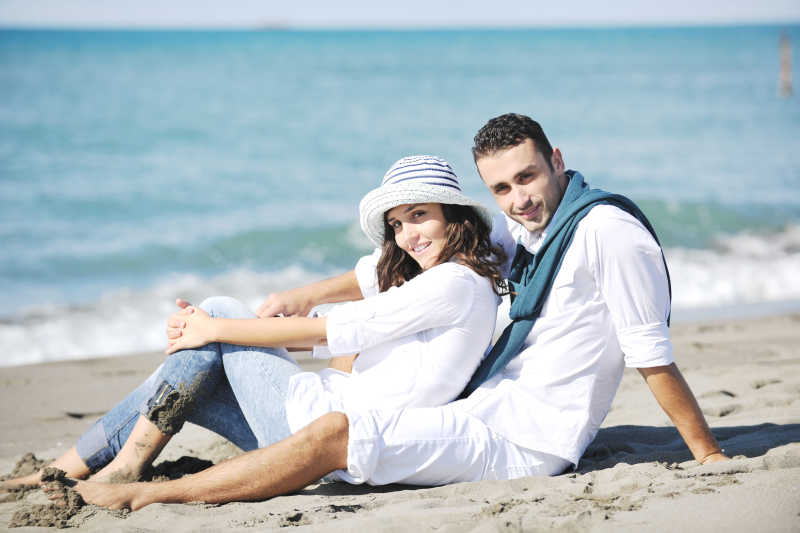 穿着白色衣服的快乐情侣在度假的美丽海滩享受浪漫的娱乐和乐趣