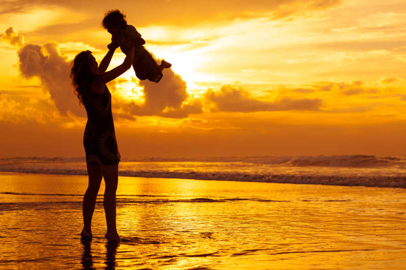 母亲和儿子在黎明时分在海滩上玩耍