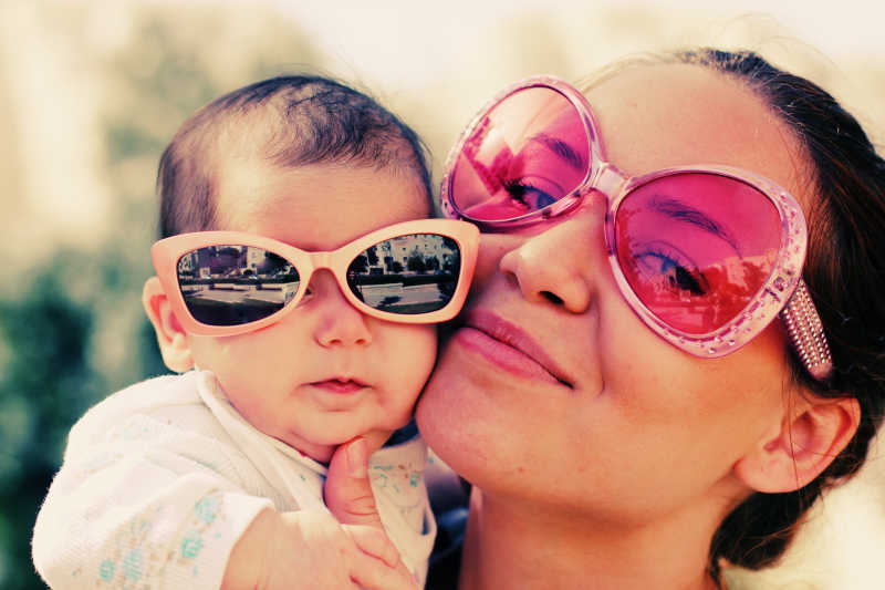 妈妈抱着婴儿戴着太阳镜微笑