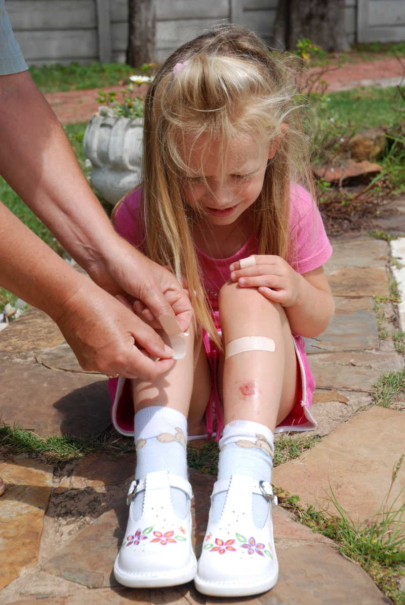 小女孩用创可贴处理腿上的伤口