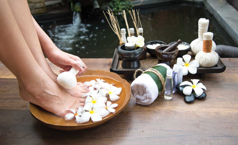 女性脚水疗中心温泉旁边木桌上的水疗和产品