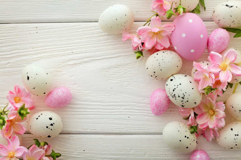 木制背景上的复活节彩蛋和粉色花朵