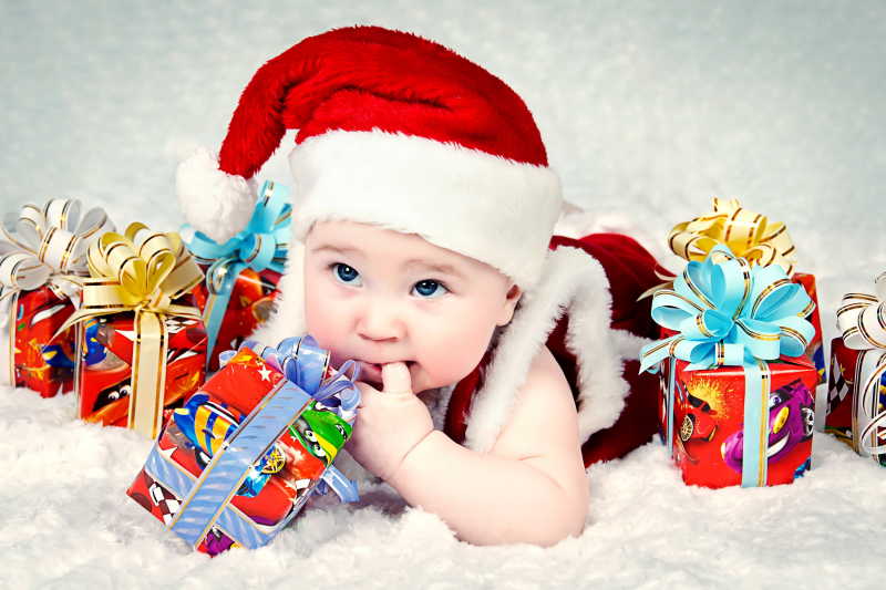 趴在毛毯上围绕着圣诞礼物的小婴儿