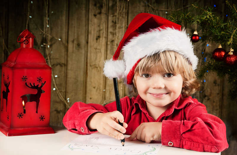 圣诞节戴着圣诞帽写信的小男孩