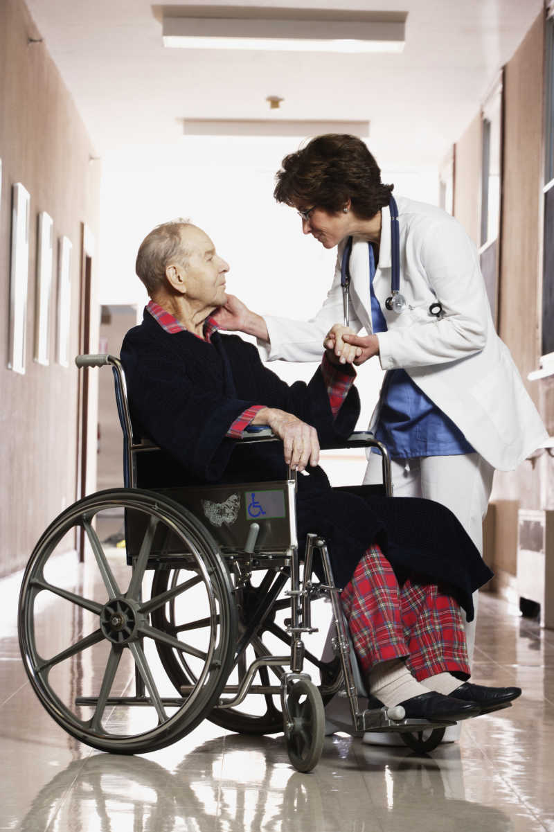 医院走廊里的女医师与轮椅上的患者交谈