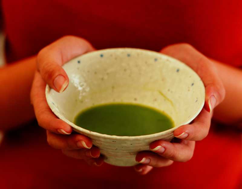双手捧着碗里的绿色液体