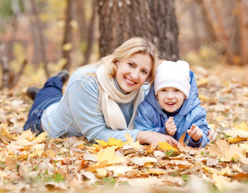 母亲和儿子一起趴在公园落叶上