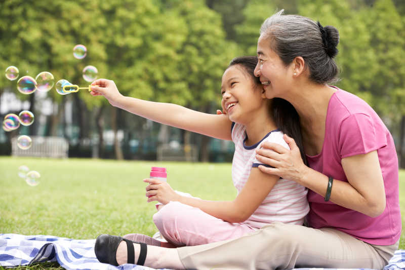 中国奶奶带孙女在公园吹泡泡