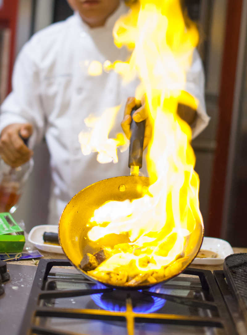 厨师在厨房用平底锅烹饪火焰