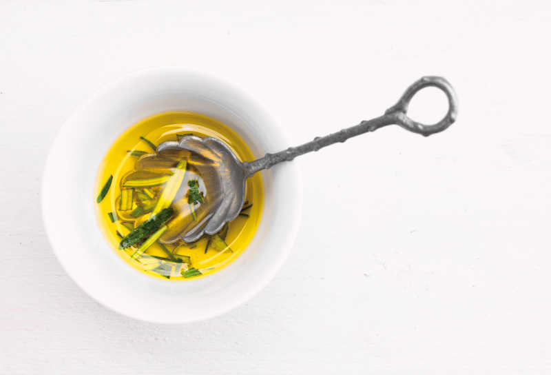 白色背景下白色碗里的橄榄油和勺子