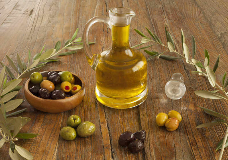 木桌上的橄榄油和各种颜色的橄榄果