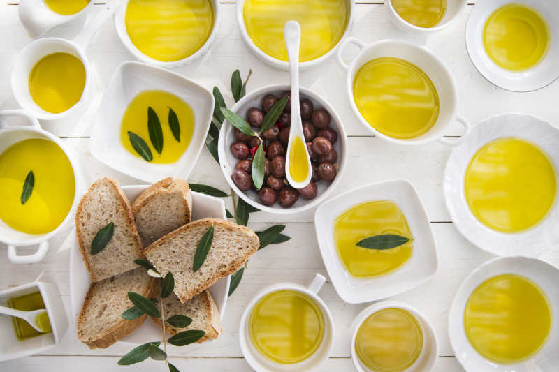 白色木桌上白色碗里的橄榄油和全麦面包