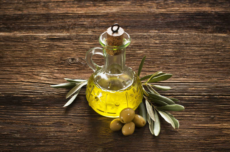 木桌上的瓶装橄榄油和橄榄枝
