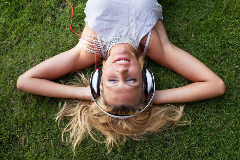 躺在草地上戴着耳机听音乐的女人
