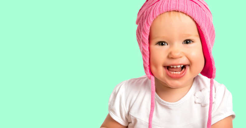 绿色背景下戴着粉色帽子的婴儿