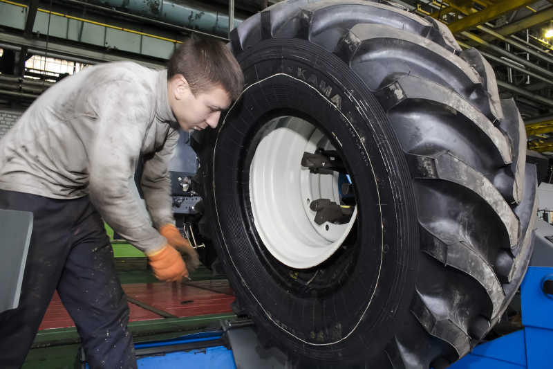 年轻的生产工人正在拆卸汽车轮胎