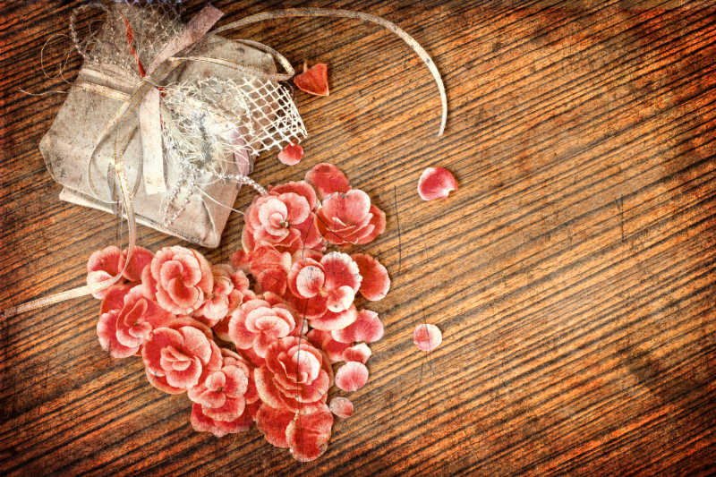 木制餐桌上的红色心形花瓣和礼物