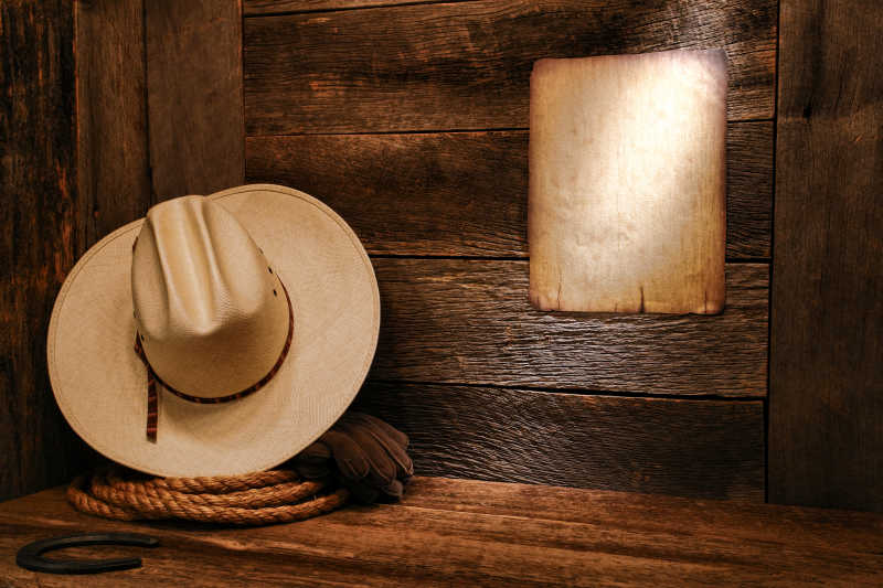 旧牧场木板墙上白草帽和正宗的西方绳套索
