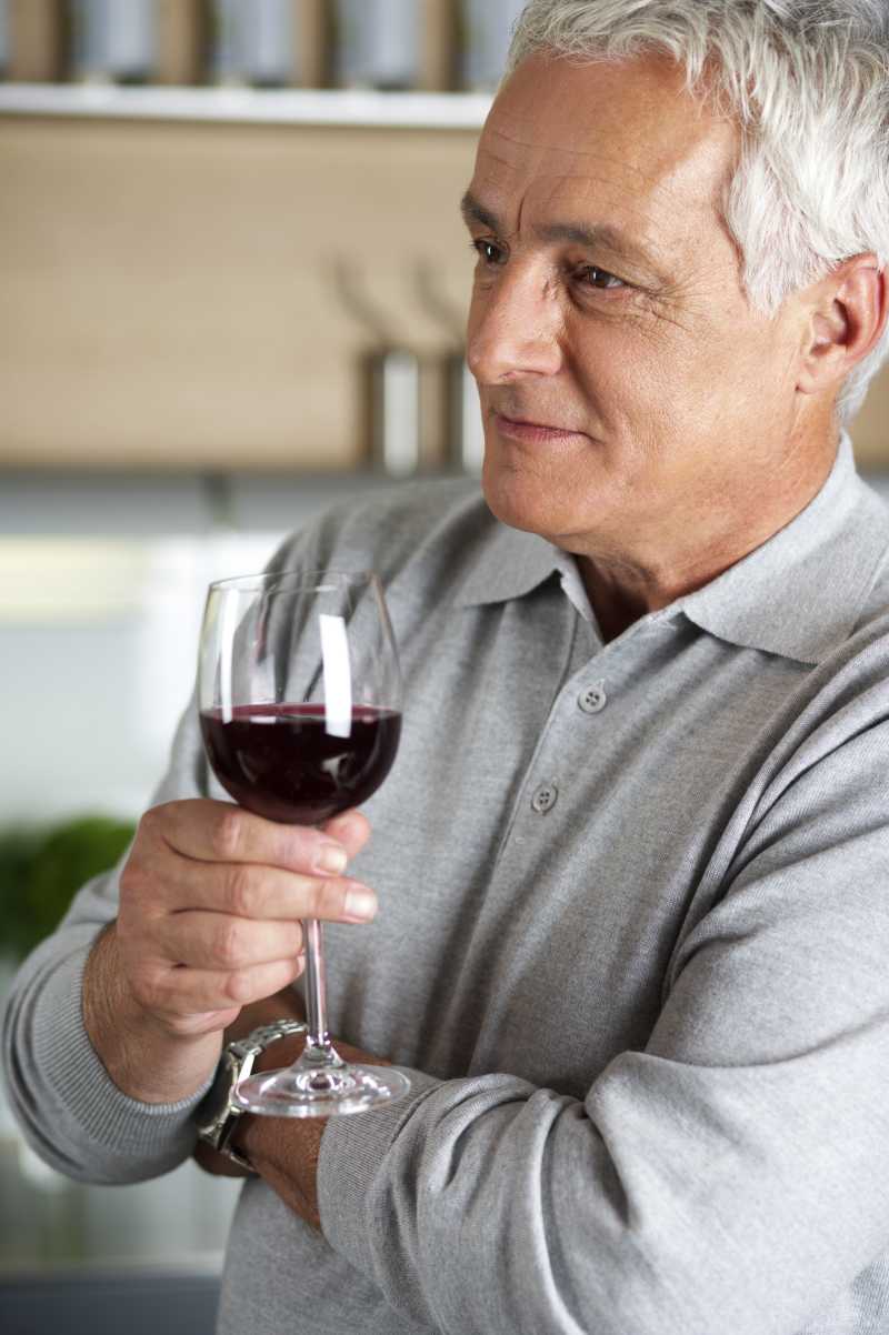 成熟的男人手里拿着一杯红酒