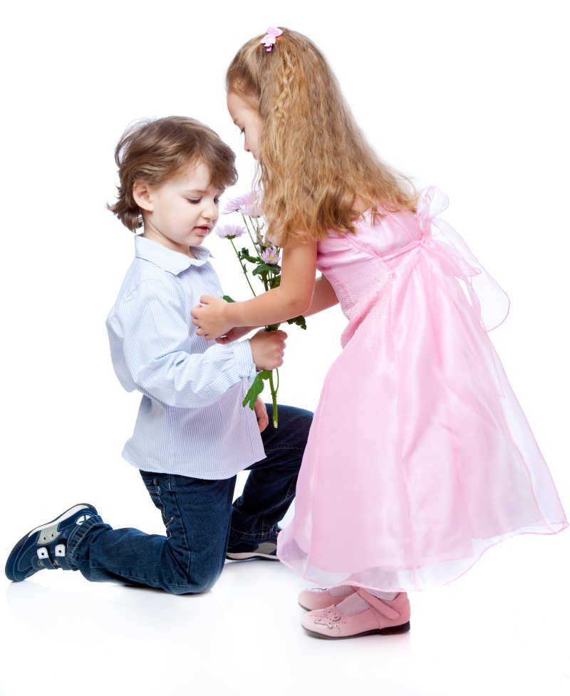 白色背景下拿着花的小男孩和穿着粉色公主裙的小女孩