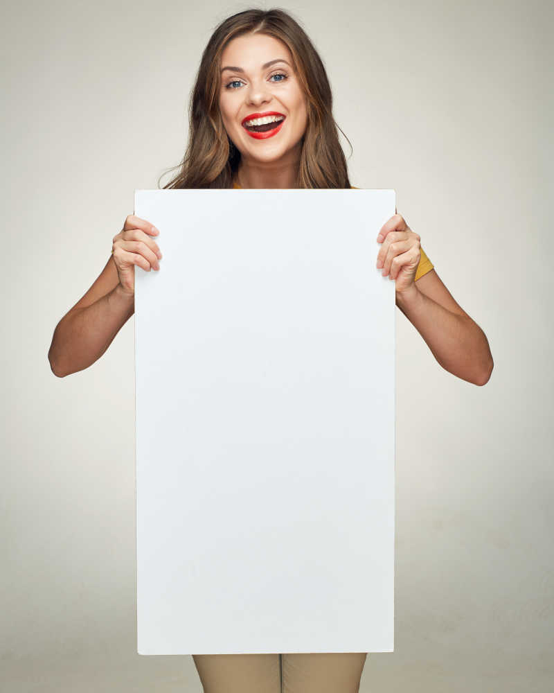 微笑的年轻女子展示白色的大牌子做广告牌