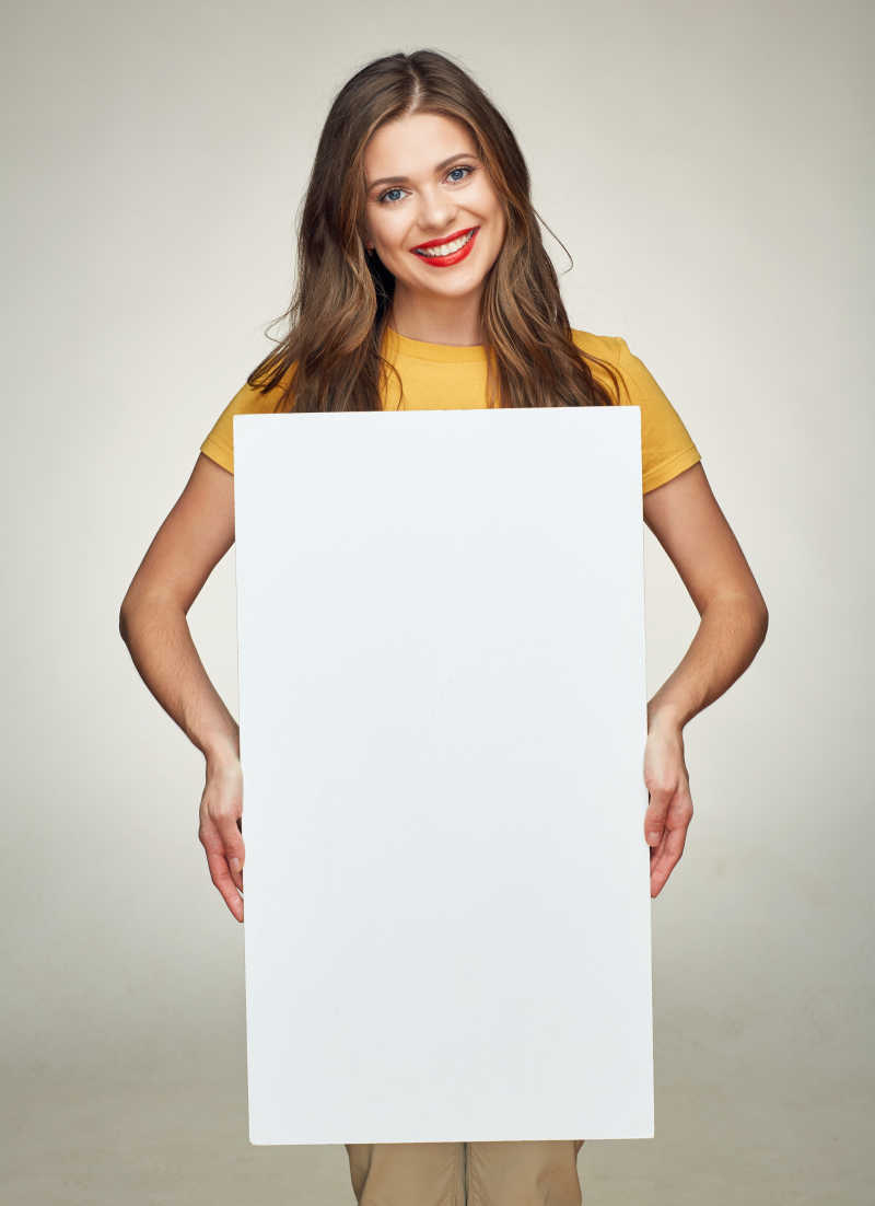 微笑的女子展示白色的大牌子做广告牌
