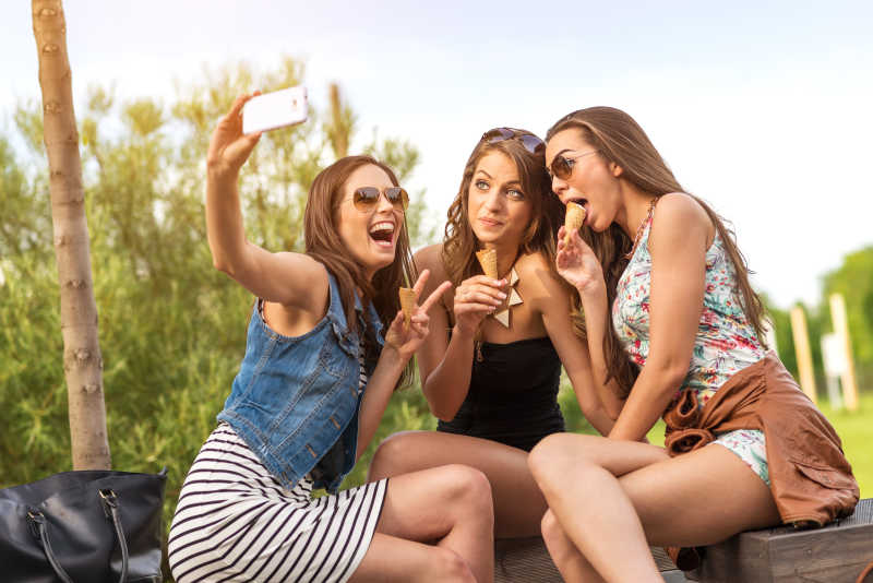 3个漂亮的女朋友吃冰淇淋用手机自拍
