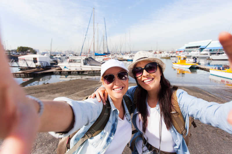 两个快乐的女性旅行者在码头自拍