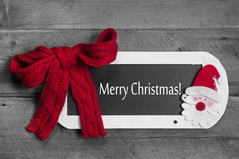 木制平台上的红色蝴蝶结与圣诞快乐留言