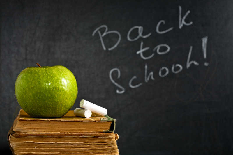 黑板上写着回到学校和书本上的苹果