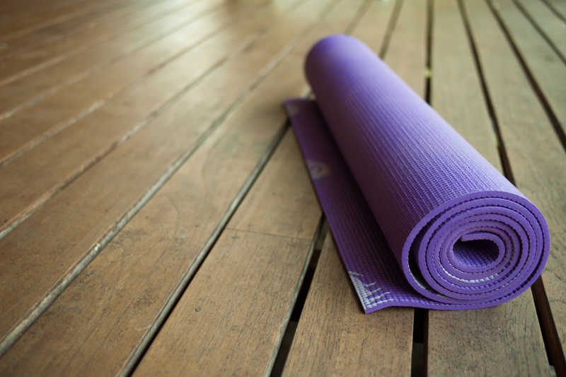 木地板上的紫色瑜伽垫