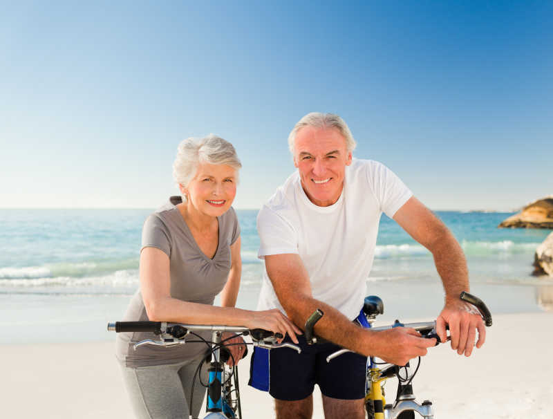 在海滩上骑自行车的老夫妇