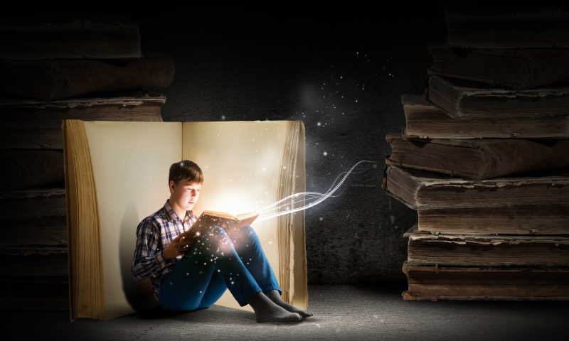 小男孩正在阅读一本发光的魔法书