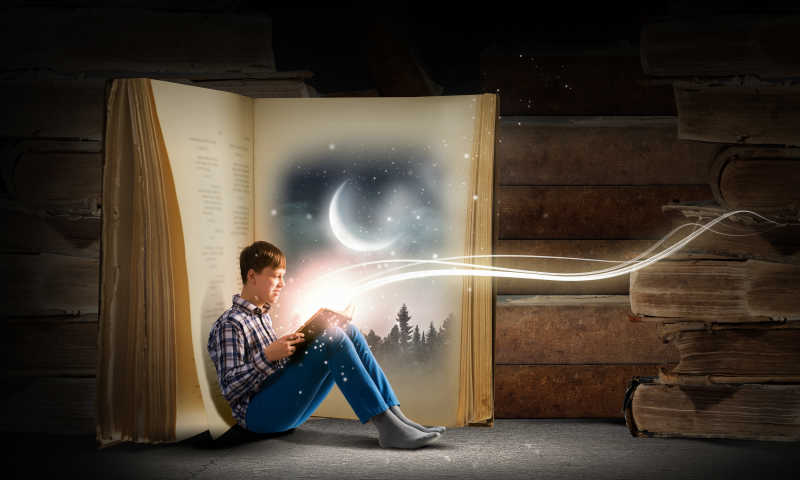 男孩在书扉间看书同时手上的书散发出绚丽的光束