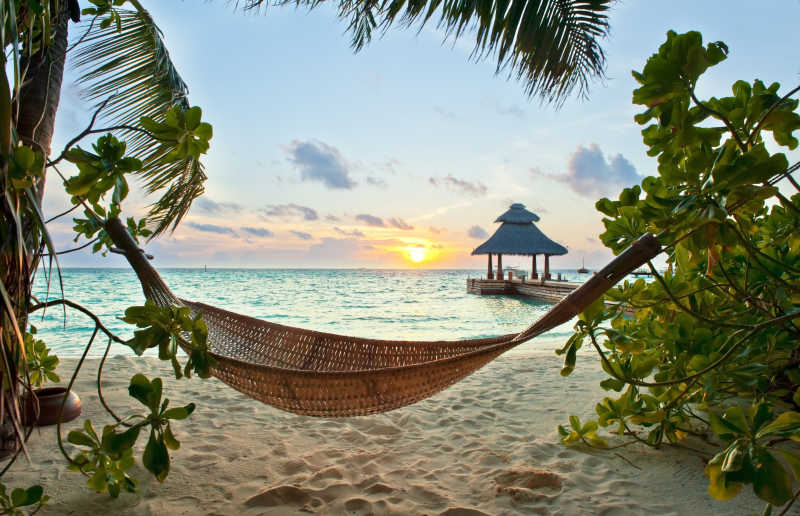 日落时分马尔代夫热带海滩的空吊床