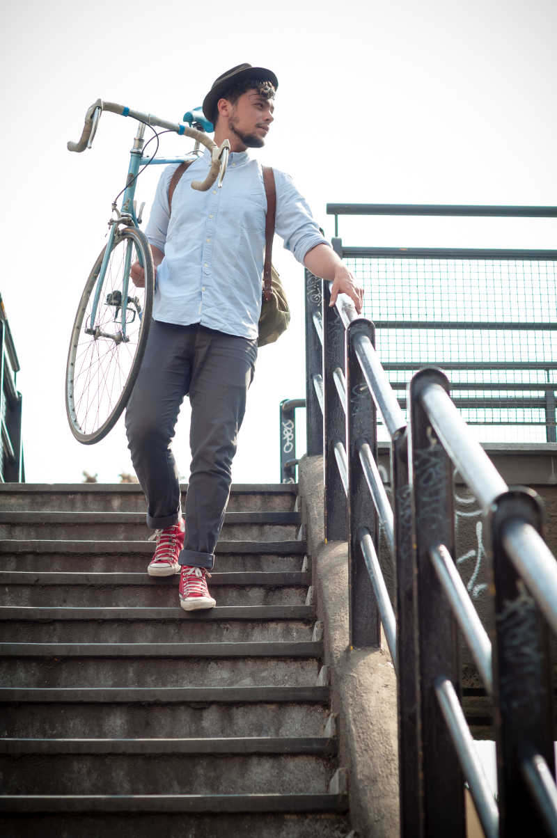时髦的年轻人在城市中扛着自行车
