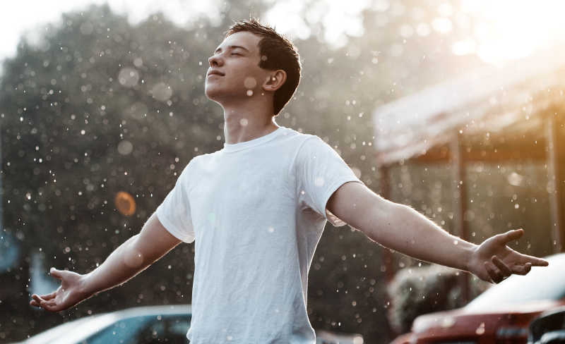 张开双手站在雨中的少年