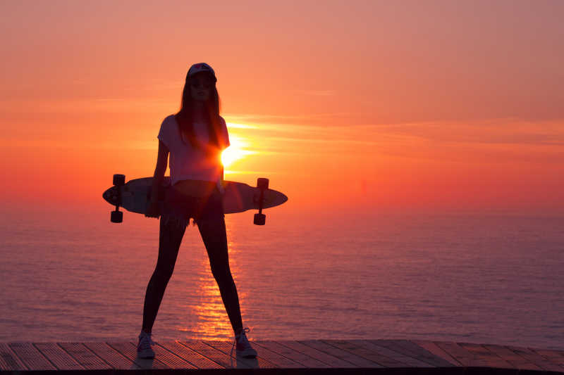 海边落下拿着滑板的女孩