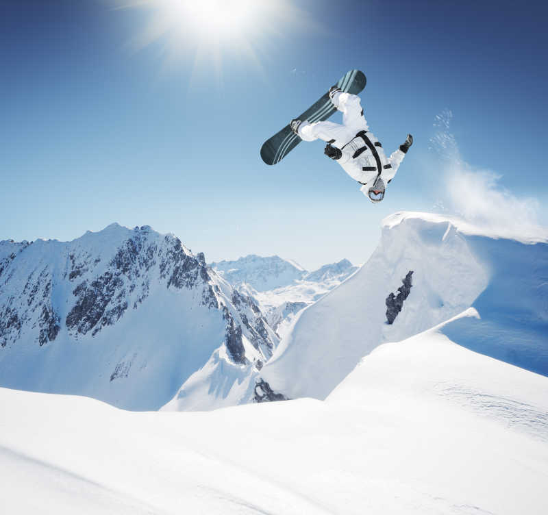 蓝天阳光下腾空而起的单板滑雪者