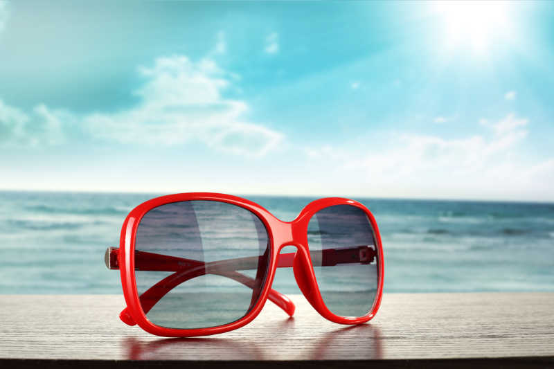 海滩背景下的红色太阳镜