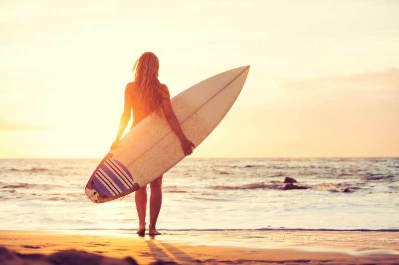 日落时分海滩上美丽性感冲浪女郎