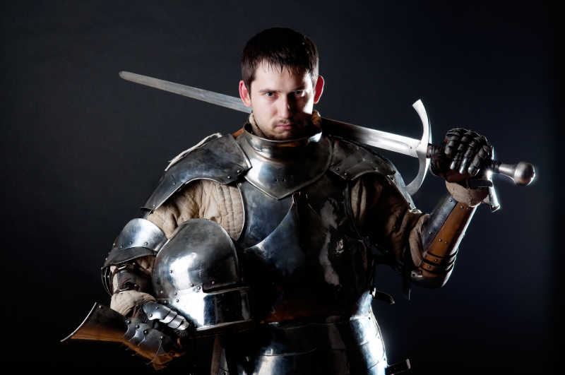 黑背景中的拿着剑和头盔的伟大骑士