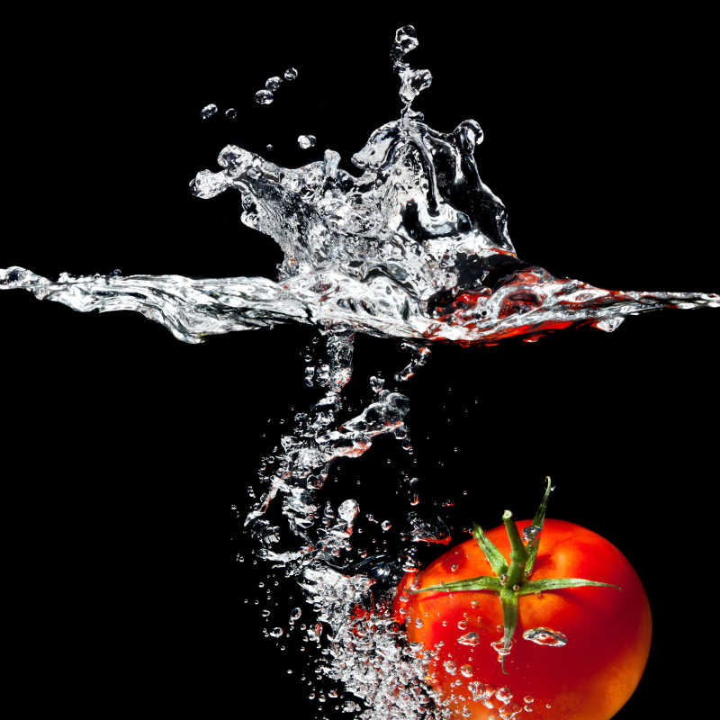 黑色背景下的掉入水中的番茄