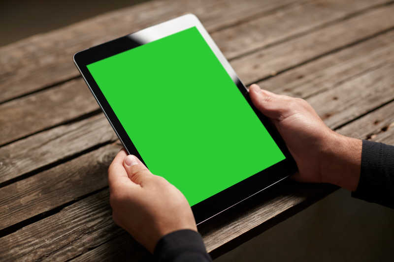 双手拿着的绿色屏幕数字平板电脑