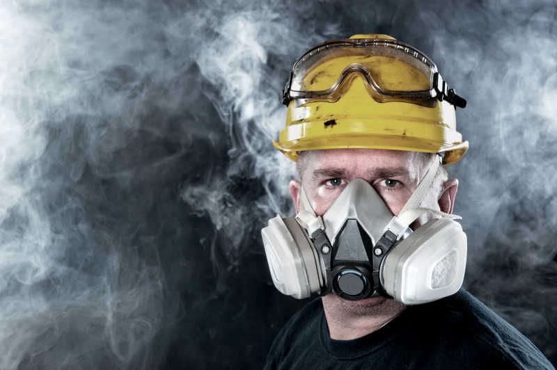 烟雾缭绕的工厂里员工戴着一个大大的防毒面具