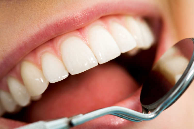 用镜子靠近病人的牙齿做口腔检查
