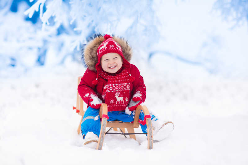 坐在雪橇上笑的婴儿